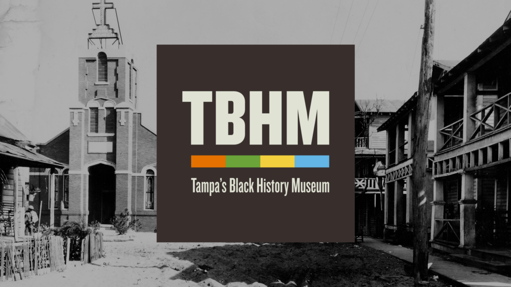Promotional graphic for Tampa’s Black History Museum. A black-and-white archival photograph of The Scrub in Tampa, Florida, in 1933 fills the background, showing a church and neighborhood buildings. The museum’s logo appears centered on top, with large “TBHM” letters, a four-color horizontal bar, and the words “Tampa’s Black History Museum.”
