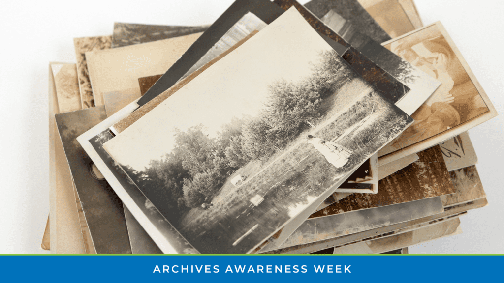 Stack of old family photographs with Archives Awareness Week banner